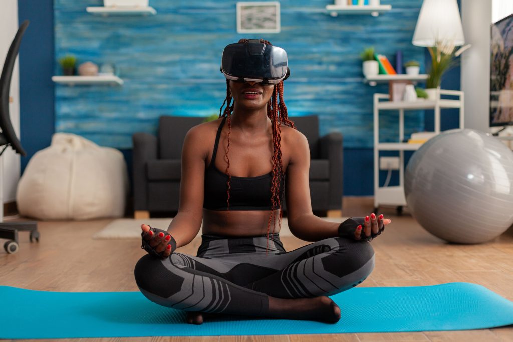 young-woman-experiencing-virtual-wellness-training-body-mind-meditating-lotus-pose-sitting-yoga-mat-home-living-room